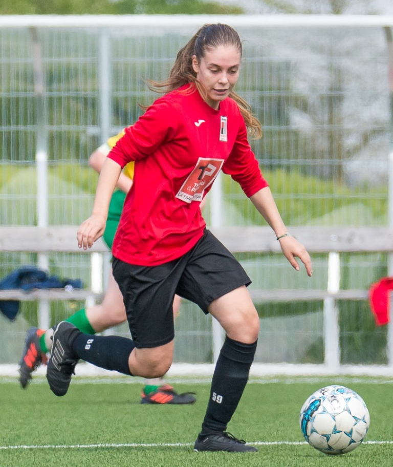 Une footbaleuse en rouge et noir derrière un ballon